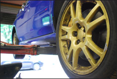 Gold wheel of a blue Impreza up on the ramp